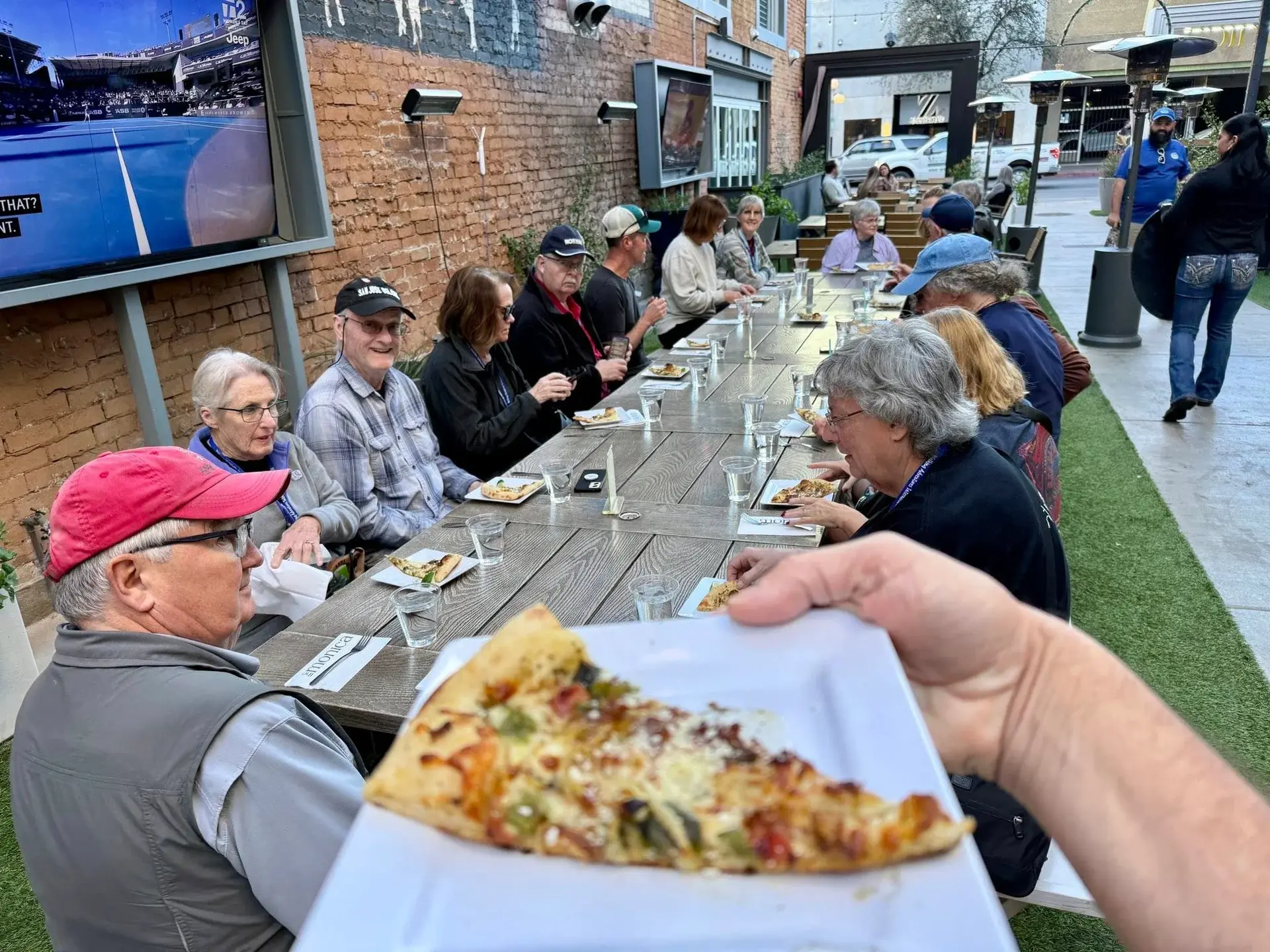 WAI group sharing a long outdoor table meal together, laughing and relaxed — the social side of a walking tour