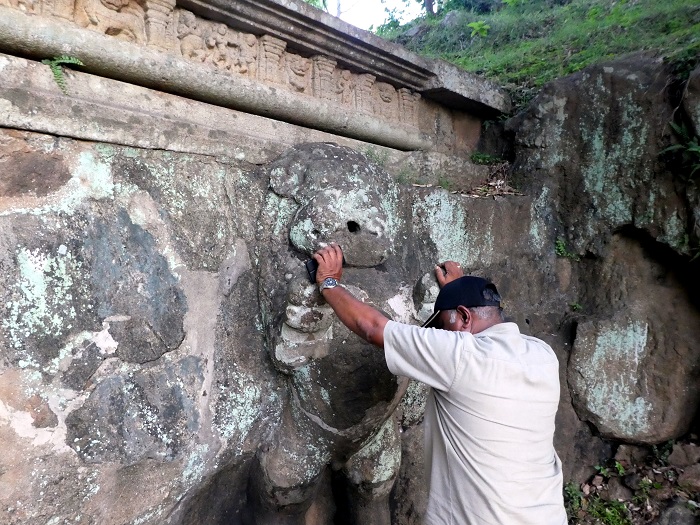 Prasantha demonstrating how pilgrims would purify themselves in the stream of water coming from the lion's mouth